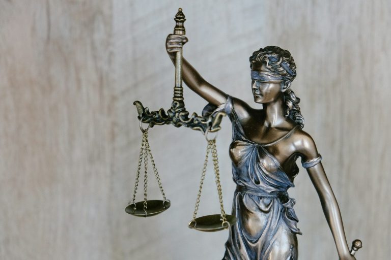 Rotes Buch mit Waage, Symbol für Recht und Gerechtigkeit.